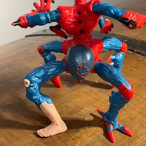K&ouml;nnte beinhalten: Eine rote und blaue Actionfigur von Spider-Man mit mehreren Beinen und Armen. Die Figur steht in einer stehenden Position mit gespreizten Beinen. Die Figur ist aus Kunststoff und hat eine detaillierte Bemalung.
