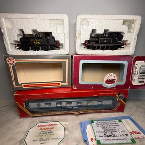 May include: A collection of model railway items, including two black locomotives and a passenger carriage, all in their original packaging. One locomotive is marked "Southern 636". Includes limited edition certificates.