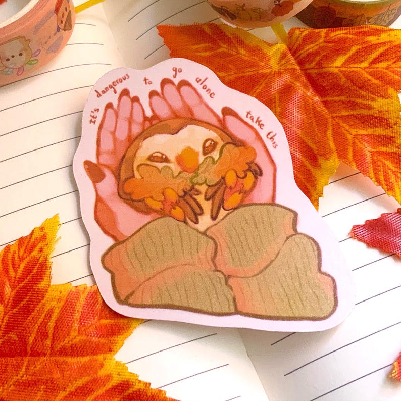 May include: A sticker with a hand holding a small owl with autumn leaves. The text on the sticker reads "It's dangerous to go alone, take this."