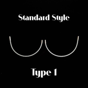 May include: Two silver-coloured, semi-circular underwire bra components are displayed against a black background. The text 'Standard Style' appears above the wires, and the text 'Type 1' is positioned below them in a white serif font.