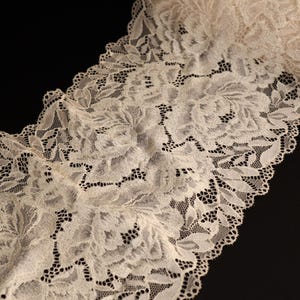 Peut inclure: Galon de dentelle ivoire avec un motif floral. La dentelle a un bord festonné.