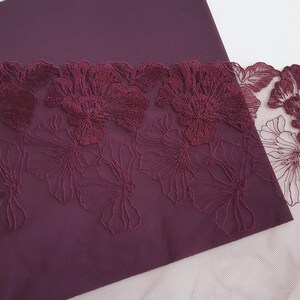 May include: Burgundy fabric with a burgundy floral lace trim. The lace is delicate and has a floral pattern.