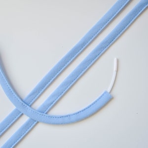 May include: Two light blue fabric straps with a white plastic cord threaded through one of the straps.