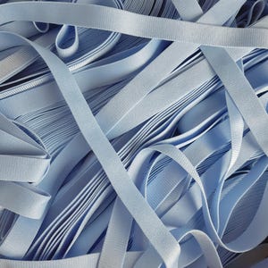 May include: A pile of light blue elastic ribbon. The ribbon is folded and stacked in a random pattern.