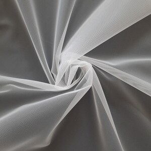 May include: White tulle fabric with a soft, delicate texture. The fabric is gathered and twisted, creating a swirling pattern.