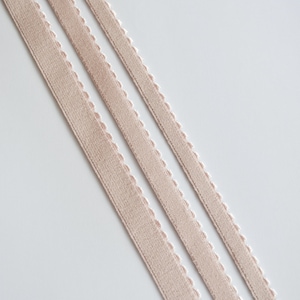May include: Three strands of beige elastic ribbon with a scalloped edge.