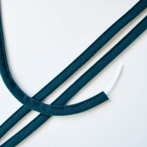 May include: Two strands of teal blue fabric cord with a white elastic cord attached to one end.