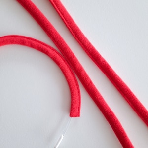 May include: Two red cords with a white cord running through one of them.
