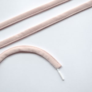 May include: Two pieces of pink velvet ribbon with a white cord attached to one end.