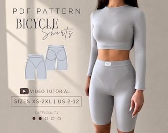 Puede incluir: Un patrón PDF para pantalones cortos de ciclismo con una camiseta corta de manga larga gris claro y pantalones cortos de cintura alta a juego. La imagen incluye el texto: PDF PATTERN BICYCLE SHORTS, VIDEO TUTORIAL, SIZES XS-2XL | US 2-12.