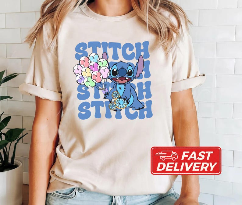 May include: A beige t-shirt with a blue Stitch character holding a blue and white balloon. The text "Stitch Stitch Stitch" is printed in blue on the shirt.
