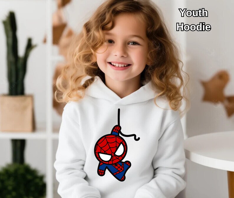 Puede incluir: Sudadera blanca para j&oacute;venes con una imagen de dibujos animados de Spiderman colgando de una telara&ntilde;a. La sudadera tiene una capucha con cord&oacute;n.
