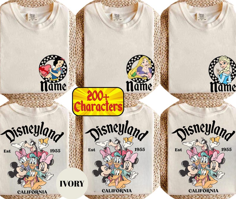May include: Ivory-colored t-shirts featuring Disney characters and the Disneyland logo. The shirts display Snow White, Rapunzel, and Elsa designs, along with a group of Disney characters. The text "Name" appears below the character images.