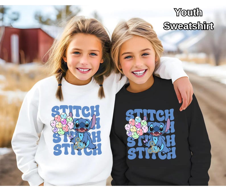May include: Two children wearing matching white and black youth sweatshirts with a blue Stitch character holding balloons and the text "Stitch" repeated in a retro font.