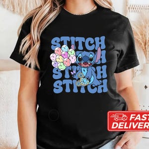 May include: Black t-shirt with a blue Stitch character holding a bunch of colorful balloons. The text "Stitch Stitch" is printed in white on the shirt.