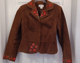 May include: A brown suede jacket with embroidered flowers on the collar, cuffs, and front. The jacket has a button closure and a fitted silhouette.