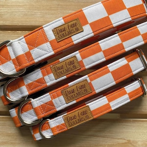 May include: Four orange and white checkered dog collars with silver hardware. Each collar has a brown leather patch with the text "Dixie Lane Collars" in white.