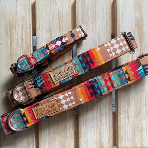 Peut inclure: Trois colliers pour chien avec un motif géométrique dans des tons de brun, rouge, orange, bleu et blanc. Les colliers ont des accessoires en argent et une étiquette en cuir marron qui indique "Dixie Lane Collars".