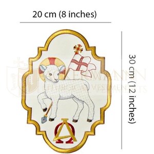 May include: White embroidered lamb with a golden halo, holding a staff with a red flag, and the Greek letters Alpha and Omega. The lamb is on a white background with a gold border. The image is 8 inches wide and 12 inches tall.