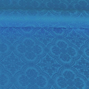 Op de afbeelding: Een close-up van een blauwe stof met een herhalend patroon van gestileerde bloemen en bladeren. De stof heeft een subtiele glans en een textuur.