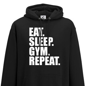 Könnte beinhalten: Schwarzer Kapuzenpullover mit weißem Text, der "EAT. SLEEP. GYM. REPEAT." lautet.