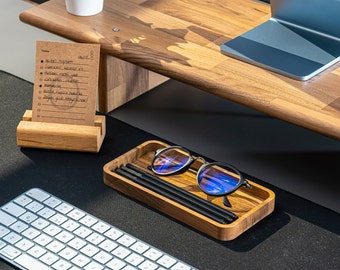May include: A white keyboard with black keys, a wooden tray with black pens and blue light blocking glasses, and a wooden stand with a note pad that says "Today" and has a list of tasks written on it.