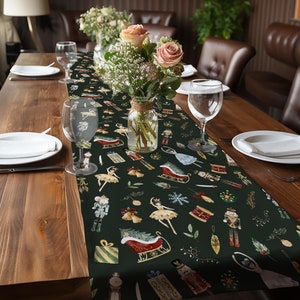 May include: A green table runner with a festive Christmas design featuring ballerinas, nutcrackers, and sleighs. The runner is decorated with gold accents and a dark green background.