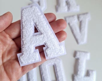 May include: White felt letters in the alphabet, including the letters A, R, V, O, and L. The letters are thick and have a fuzzy texture.