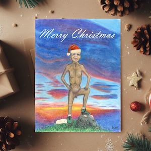 May include: A humorous Christmas card featuring a nude man wearing a Santa hat standing on a rock with a sunset background. The card reads "Merry Christmas".