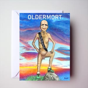 May include: A greeting card featuring a drawing of a bald, pale figure standing on a rock against a sunset sky. The figure wears a black sash with the text 'IT'S MY BIRTHDAY!' and green trainers. The word 'OLDERMORT' is printed in white at the top.