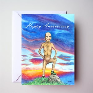 May include: A humorous greeting card featuring a cartoon drawing of a naked man standing on a rock against a sunset backdrop. The card reads "Happy Anniversary".