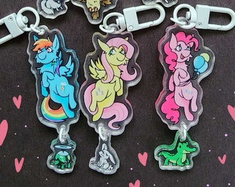 May include: Set of eight colorful cartoon character keychains featuring My Little Pony characters. Each keychain features a different pony with a unique design and color scheme. The keychains are made of clear acrylic and have a metal ring for attaching to keys or bags.