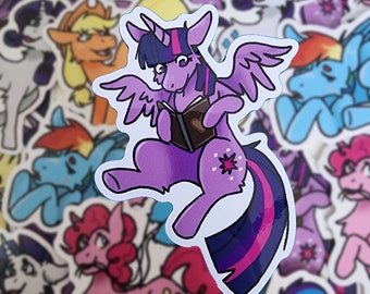 May include: A purple and pink cartoon pony with a blue and pink mane and tail, wearing a purple dress and holding a brown book. The pony has a white horn and wings. The pony is sitting on a white background.