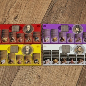 May include: Four game card organizers, each with a different color: red, yellow, purple, and white. Each organizer has a circular card holder with a portrait of a person, and a row of card slots.