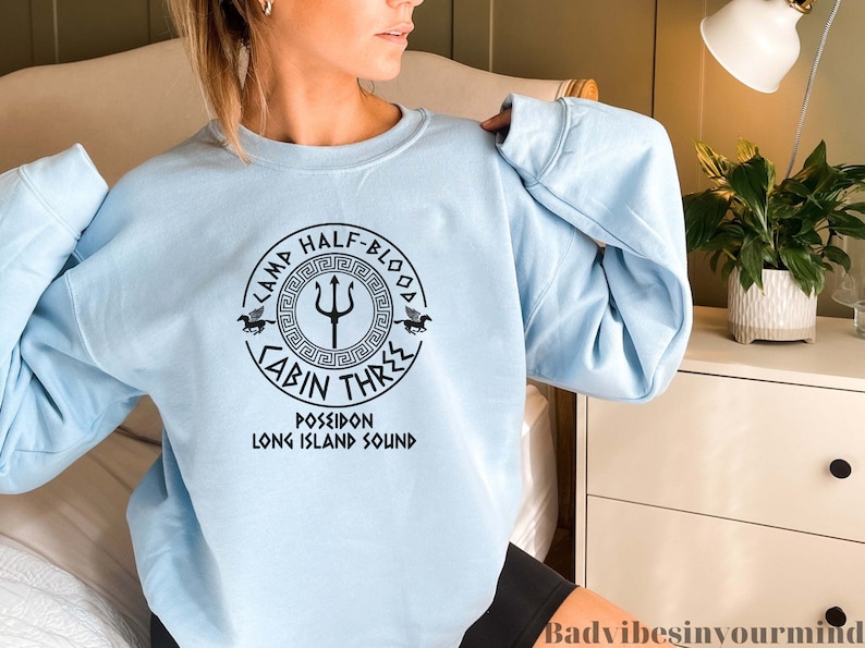 May include: Light blue sweatshirt with a black graphic of a Greek symbol and the text "Camp Half-Blood Cabin Three Poseidon Long Island Sound".