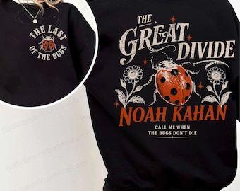 Può includere: Una felpa nera con una piccola grafica di coccinella sul petto con il testo "THE LAST OF THE BUGS". Il retro mostra una grande coccinella, fiori e il testo "THE GREAT DIVIDE", "NOAH KAHAN" e "CALL ME WHEN THE BUGS DON'T DIE".