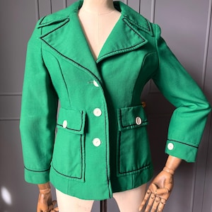 May include: A vibrant green jacket with black detailing and white buttons. The jacket features a classic design with a notched collar, two front pockets, and long sleeves. The jacket is displayed on a mannequin.