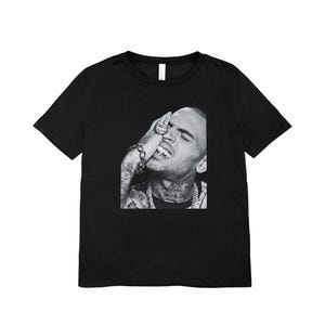 May include: A black short-sleeved t-shirt featuring a centered black and white photographic print of a person with tattoos, jewelry, and a hand covering part of their face. The text at the top reads: THIS HIGH-QUALITY TRANSPARENT PNG FILE OFFERS A CLEAR BACKGROUND, IT'S READY TO BE EASILY LAYERED ONTO YOUR PROJECTS WITHOUT THE NEED FOR ADDITIONAL EDITING. The text at the bottom reads: EFFORTLESSLY CREATE CUSTOM T-SHIRTS, HOODIES, TOTE BAGS.