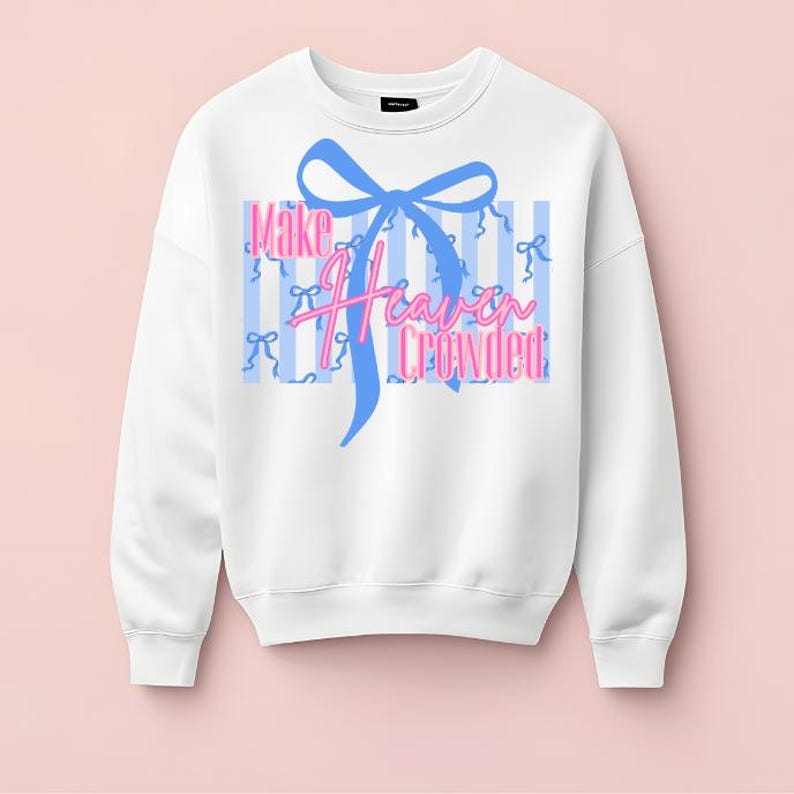 Pu&ograve; includere: Felpa bianca con fiocco blu e la scritta "Make Heaven Crowded" in rosa e blu. Il design include strisce verticali blu e piccole grafiche a fiocco. Un top casual e confortevole.