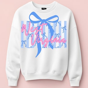 May include: White sweatshirt with a blue bow and the words "West Virginia" in pink script. The design includes blue and white striped background with small blue bows. The sweatshirt has a crew neck and long sleeves.