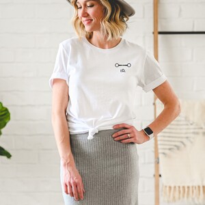 May include: White t-shirt with a black equestrian bit design and the text "EQL" underneath.