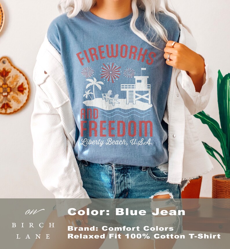 May include: Blue jean colored t-shirt with the words "Fireworks and Freedom" in red. The graphic includes fireworks, palm trees, a lifeguard tower, and the text "Liberty Beach, U.S.A."