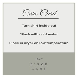 May include: Care card with instructions for washing and drying a shirt. The card says "Turn shirt inside out", "Wash with cold water", and "Place in dryer on low temperature". The card is from Birch Lane.