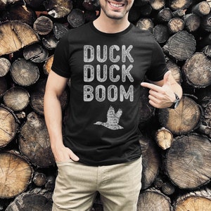 May include: Black t-shirt with a white distressed graphic that says "Duck Duck Boom" and a silhouette of a flying duck.