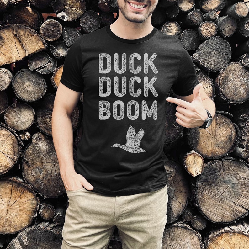 May include: Black t-shirt with a white distressed graphic that says "Duck Duck Boom" and a silhouette of a flying duck.