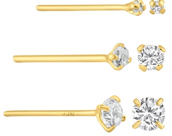 May include: Three gold nose rings with clear cubic zirconia stones. The stones are different sizes. The rings are made of 14k gold.