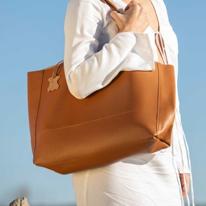a woman carrying a brown purse on a beach