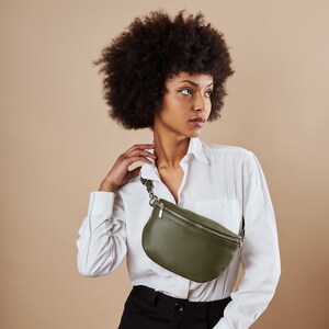 a woman in a white shirt is holding a green purse