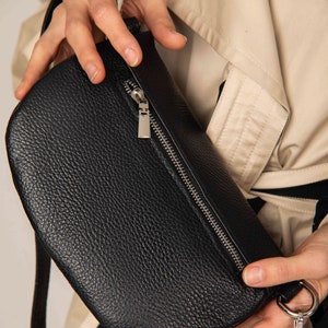 a person is holding a black purse