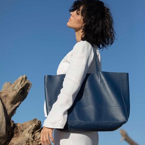 a woman in a white dress carrying a blue bag